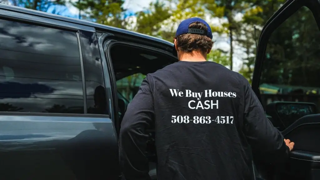 Team member in a "We Buy Houses Cash" shirt at a truck